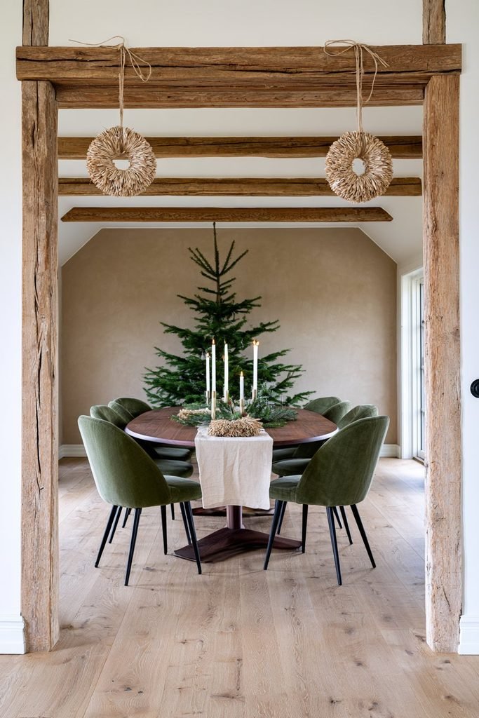 Handmade woven wheat Christmas ornaments hanging above an oak doorway in a Scandinavian dining room decorated with evergreen branches.