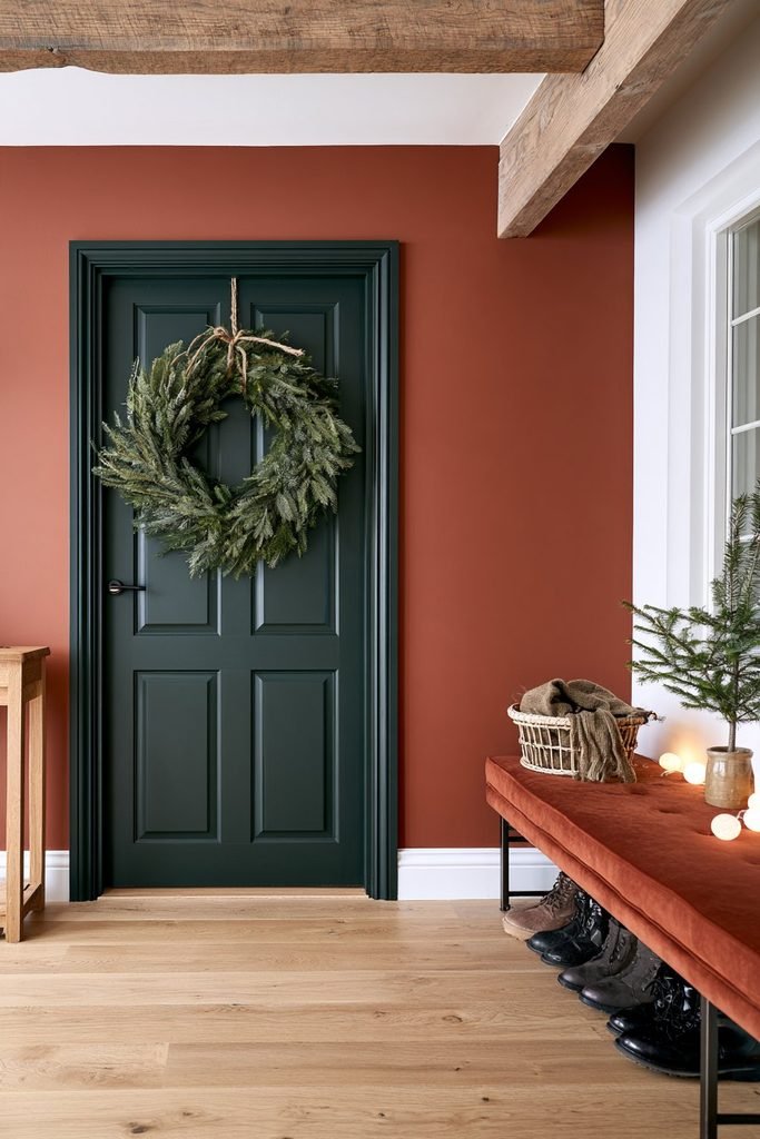 Natural evergreen Christmas wreath tied with rustic twine on a muted-green front door in a welcoming Scandinavian entrance hall.